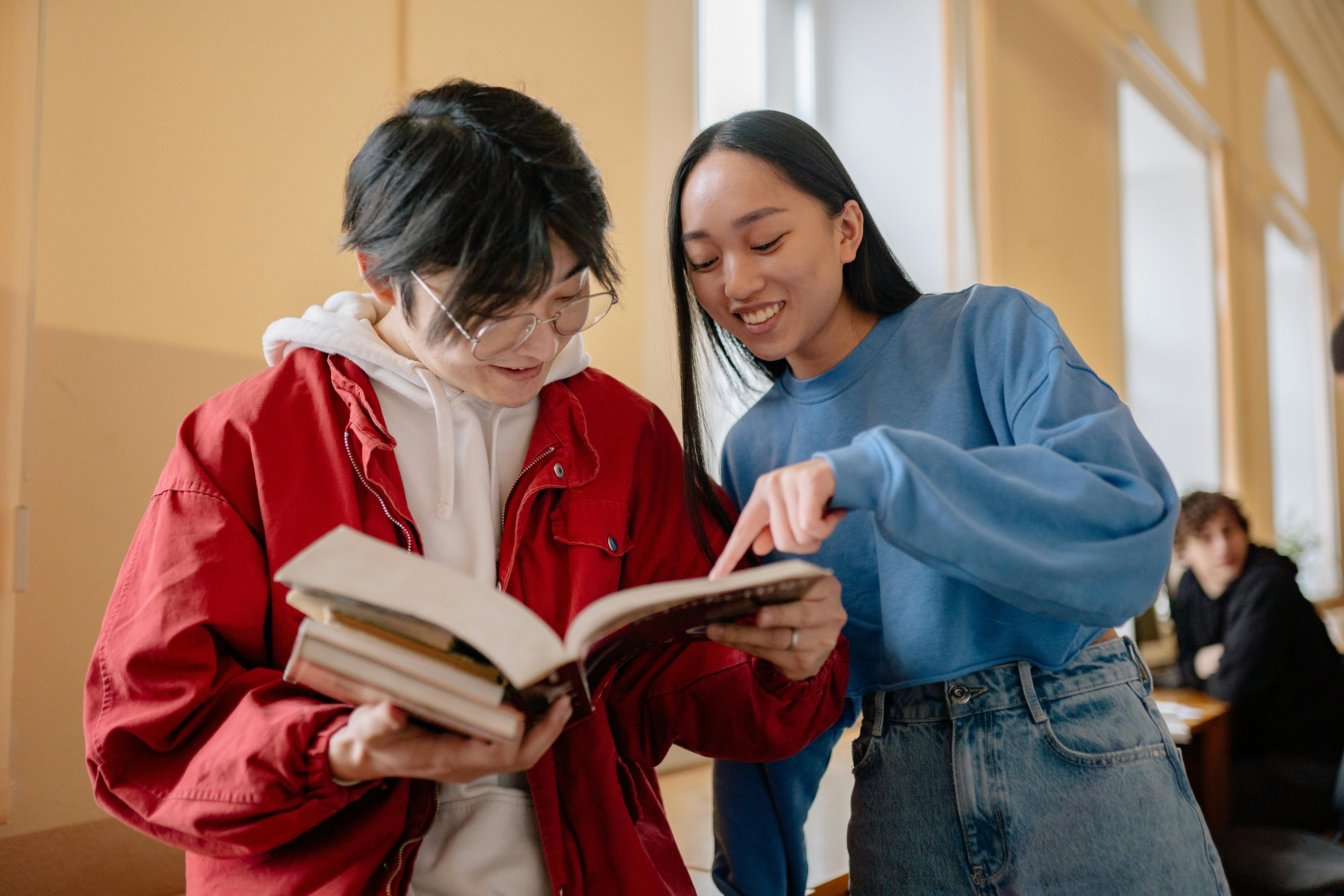 Young students collaborating and smiling while studying together in a university hallway.