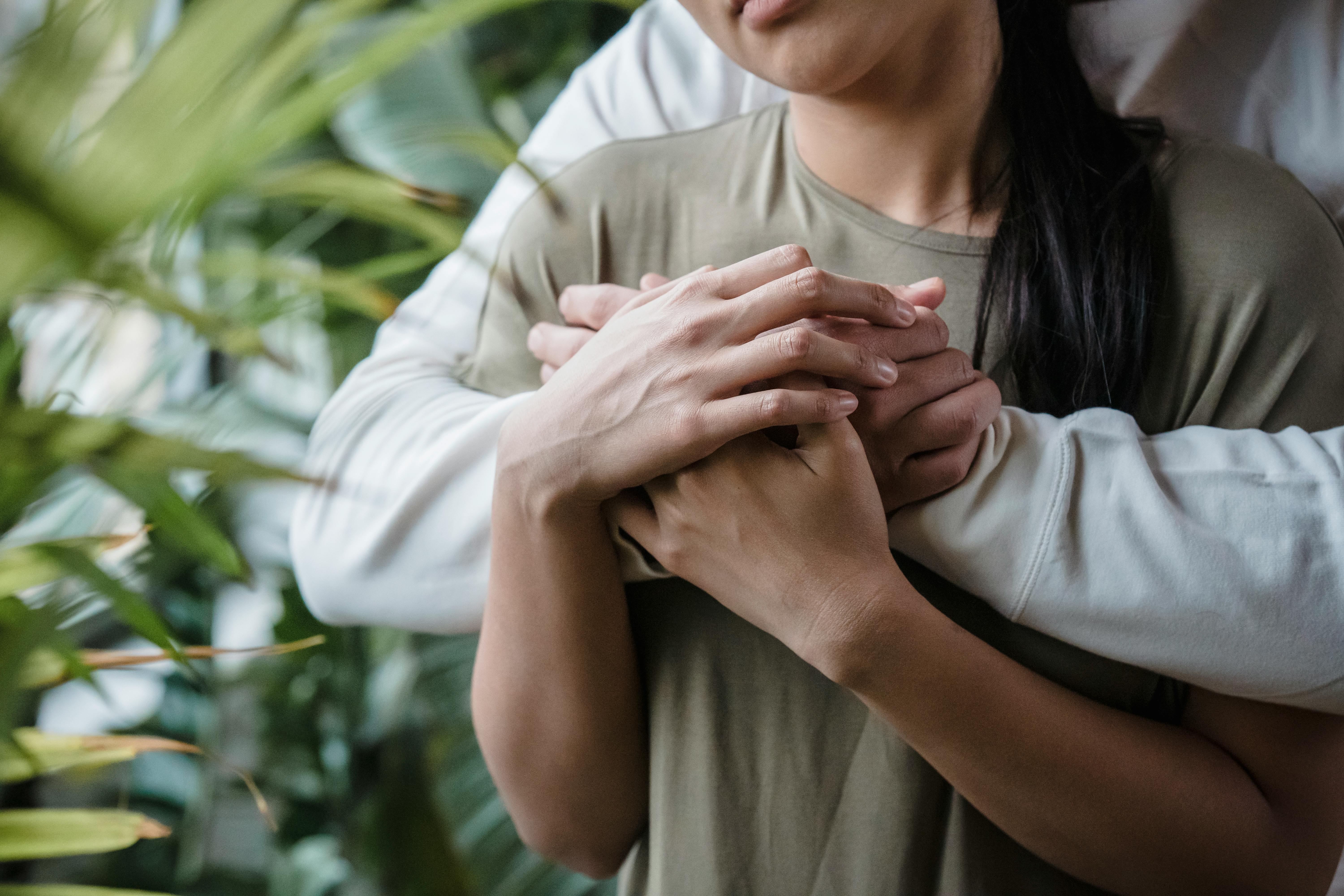 Tender embrace of a couple highlighting warmth and affection surrounded by greenery.